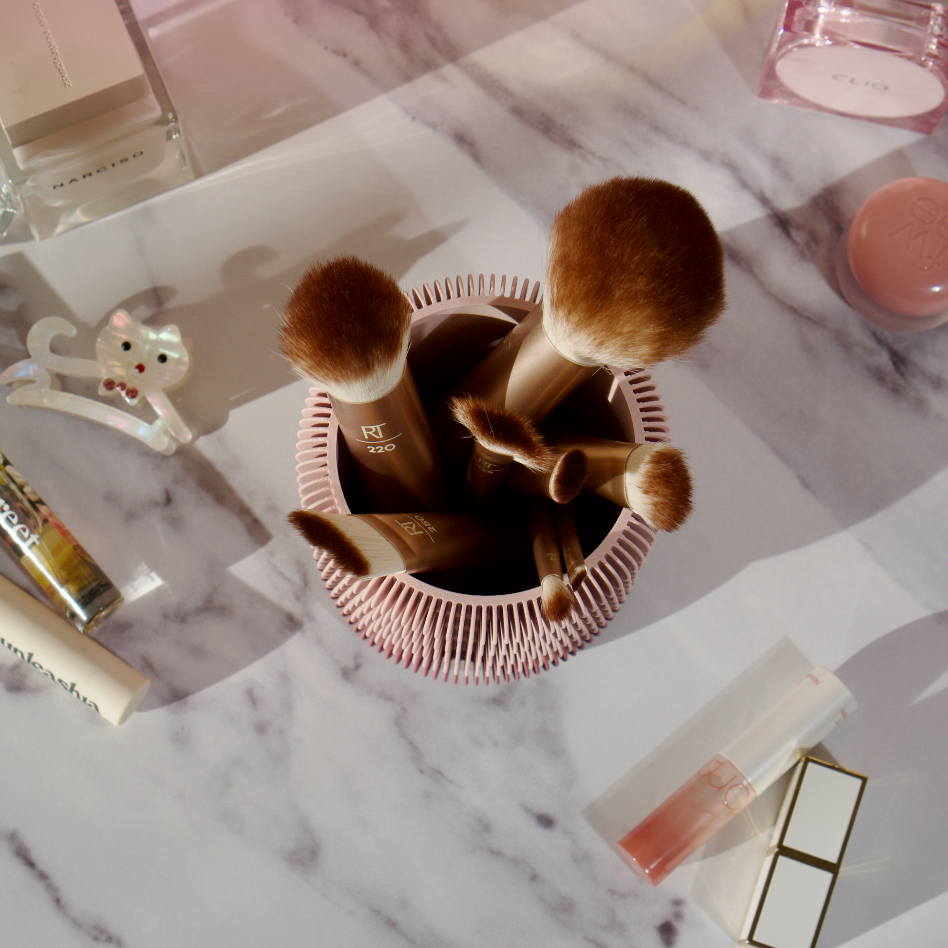 Makeup brush organiser and cleaner placed on a vanity with other beauty tools.