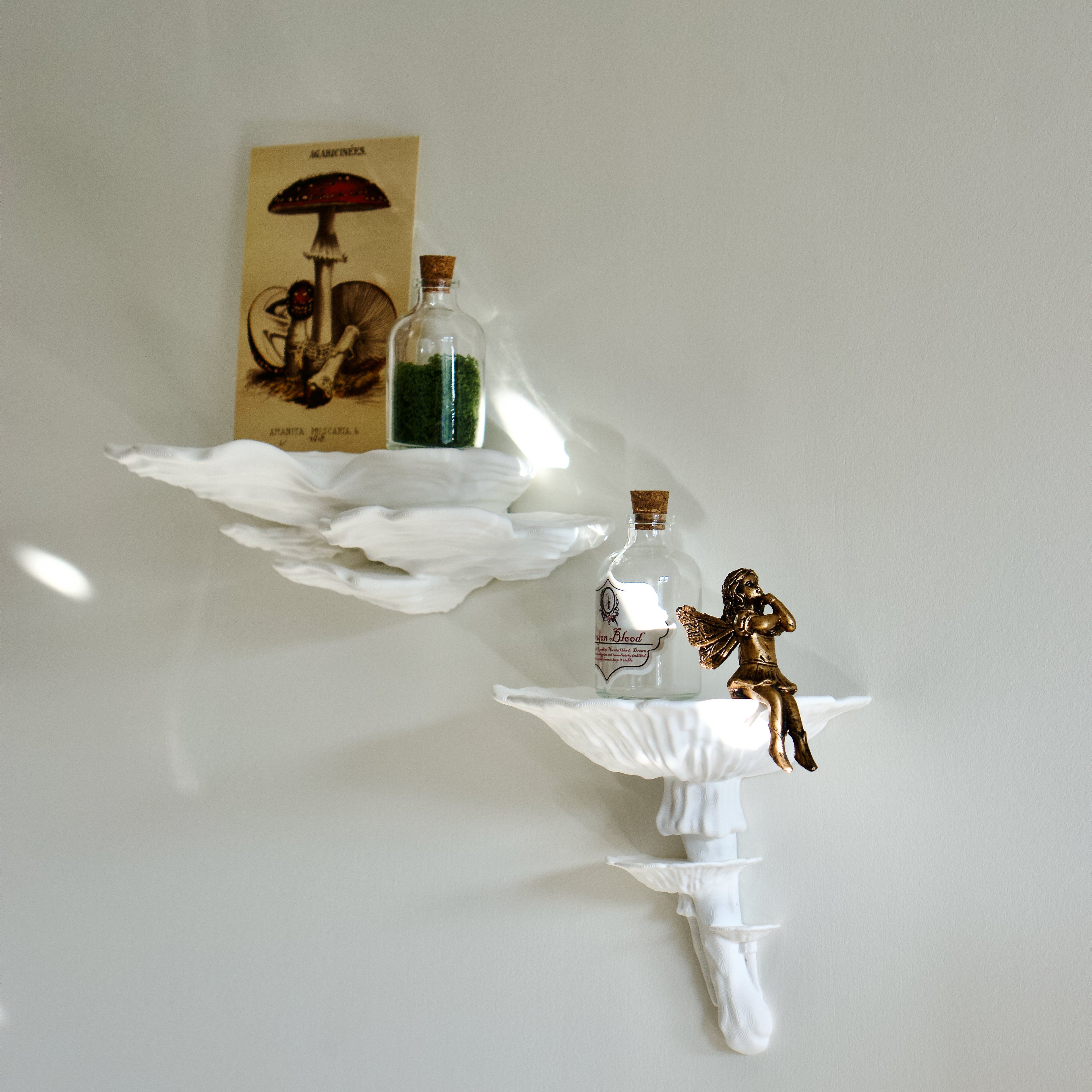 Decorative mushroom wall shelf with small bottles and a figurine on a plain white wall.