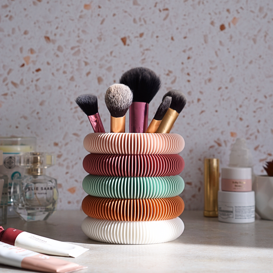Bright bubble textured storage pot holding makeup brushes and surrounded by skincare and makeup products. Perfect for home organisation. 