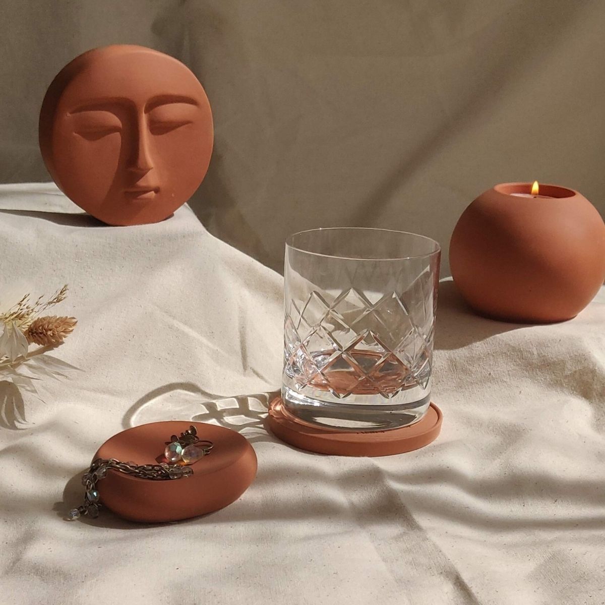 collection of stoneware style home decor in warm earthy colours including trinket dishes, candle holders, and decorative ornaments 